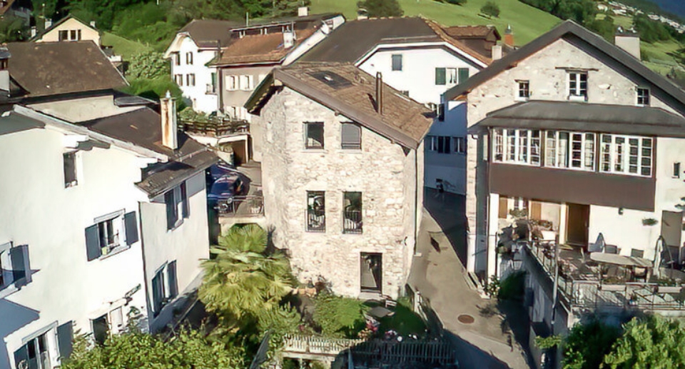 Vue aérienne d'une maison en pierre éclairée par le soleil.