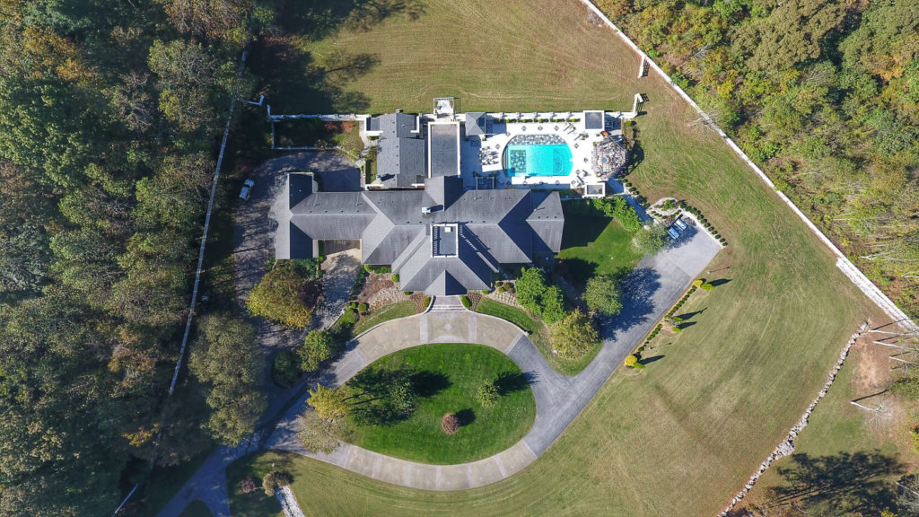 Vue aérienne de maison avec piscine, respectant la réglementation des drones en Suisse.