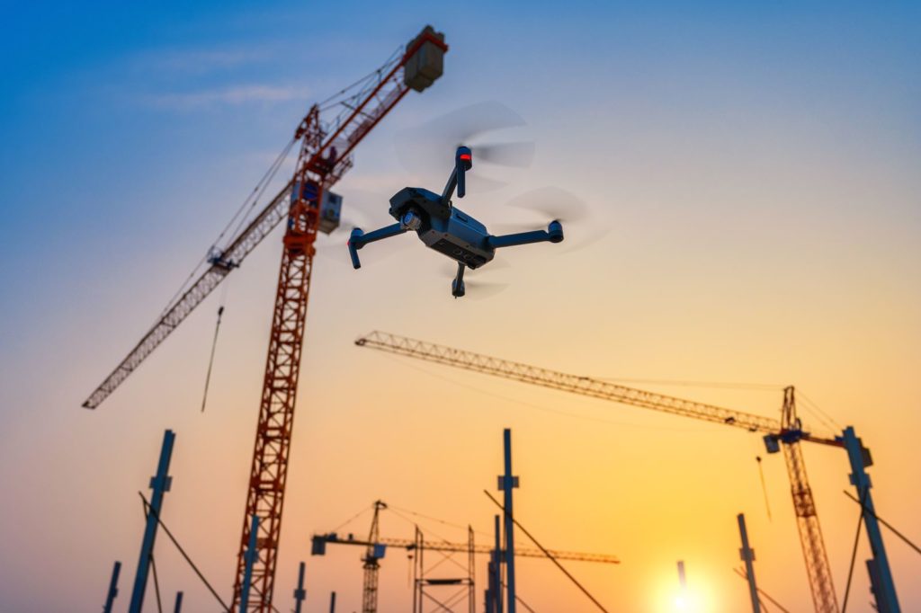Drone capturant un coucher de soleil sur un suivi de chantier avec grue de levage.